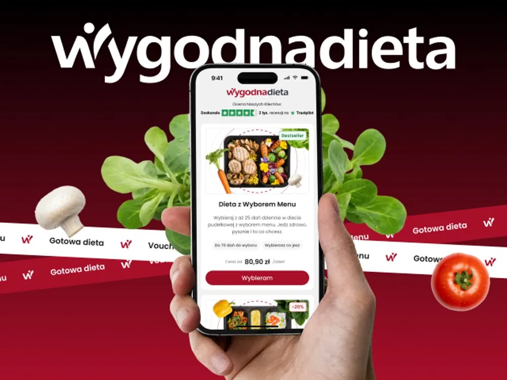 WygodnaDieta - telefon z ekranem głównym aplikacji: ocena „Doskonała" na Trustpilocie i karta diety „Dieta z Wyborem Menu" z ceną od 80,90 zł/dzień, na tle czerwonego gradientu z warzywami.