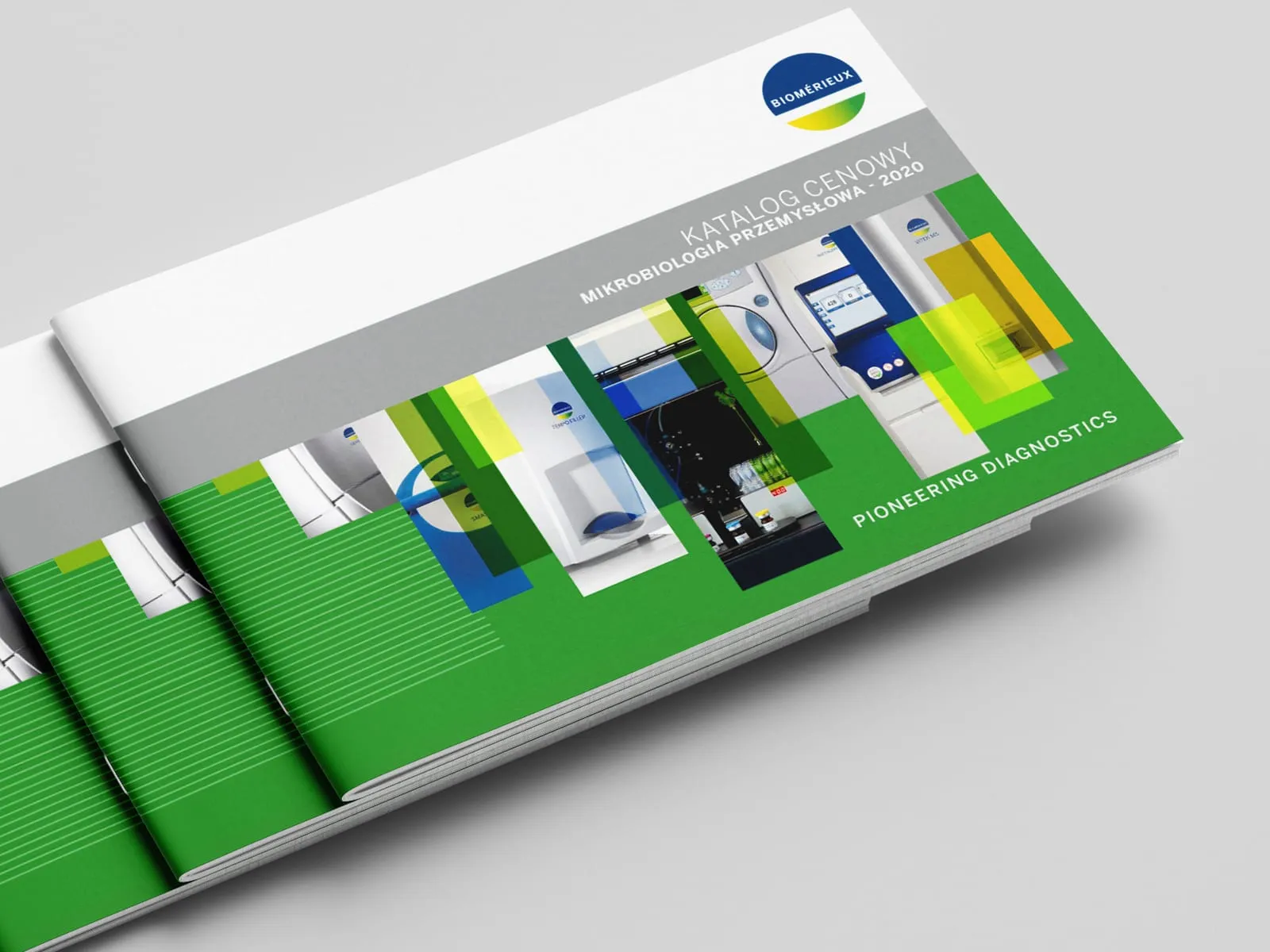 Stos egzemplarzy katalogu bioMérieux „Katalog Cenowy. Mikrobiologia Przemysłowa - 2020" z logo firmy i napisem „Pioneering Diagnostics" na zielonej okładce ze zdjęciami aparatury laboratoryjnej.