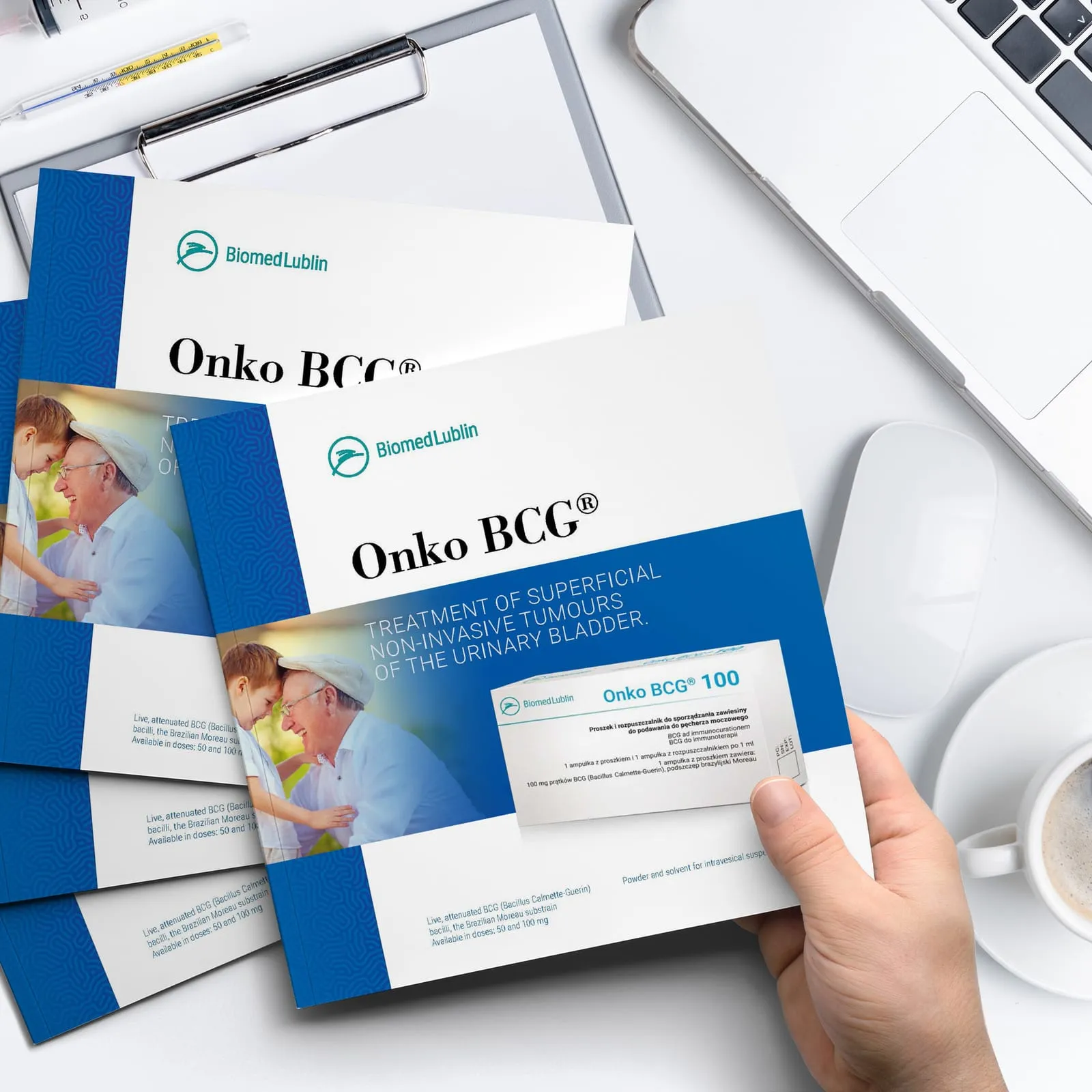 Biomed Lublin - katalog Onko BCG® trzymany w dłoni, obok stos złożonych folderów z logo Biomed Lublin i opakowanie preparatu Onko BCG® 100.