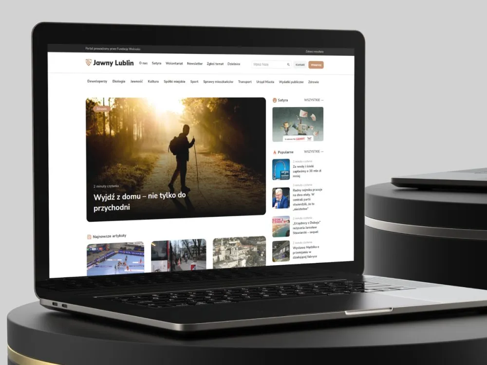 Jawny Lublin - laptop z otwartą stroną główną portalu: artykuł wiodący „Wyjdź z domu - nie tylko do przychodni", menu kategorii miejskich i kolumna z popularnymi tekstami.