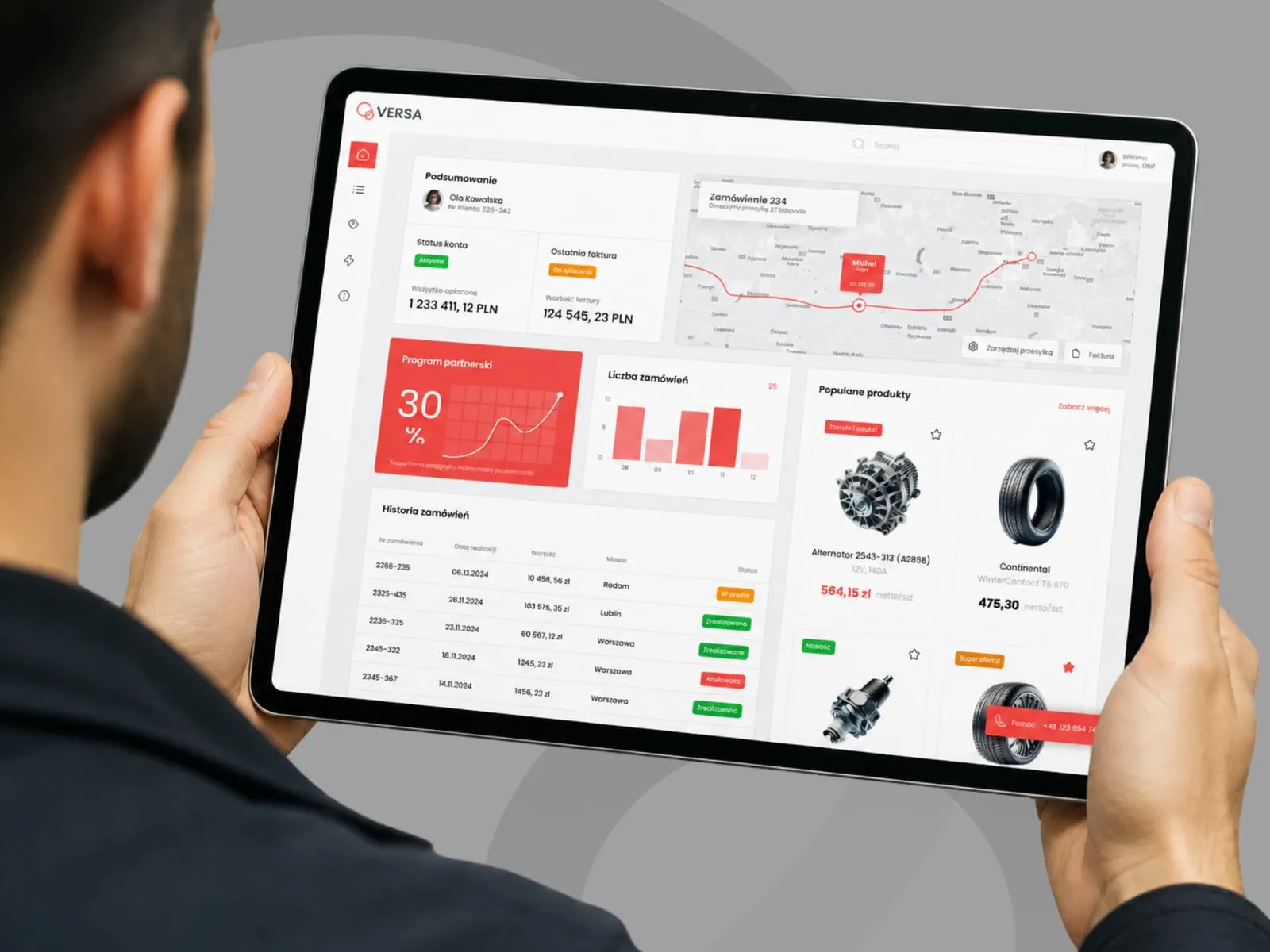 VERSA - panel B2B dystrybutora części samochodowych otwarty na tablecie trzymanym w dłoniach: podsumowanie konta, mapa śledzenia przesyłki, program partnerski z rabatem 30%, historia zamówień i lista popularnych produktów.