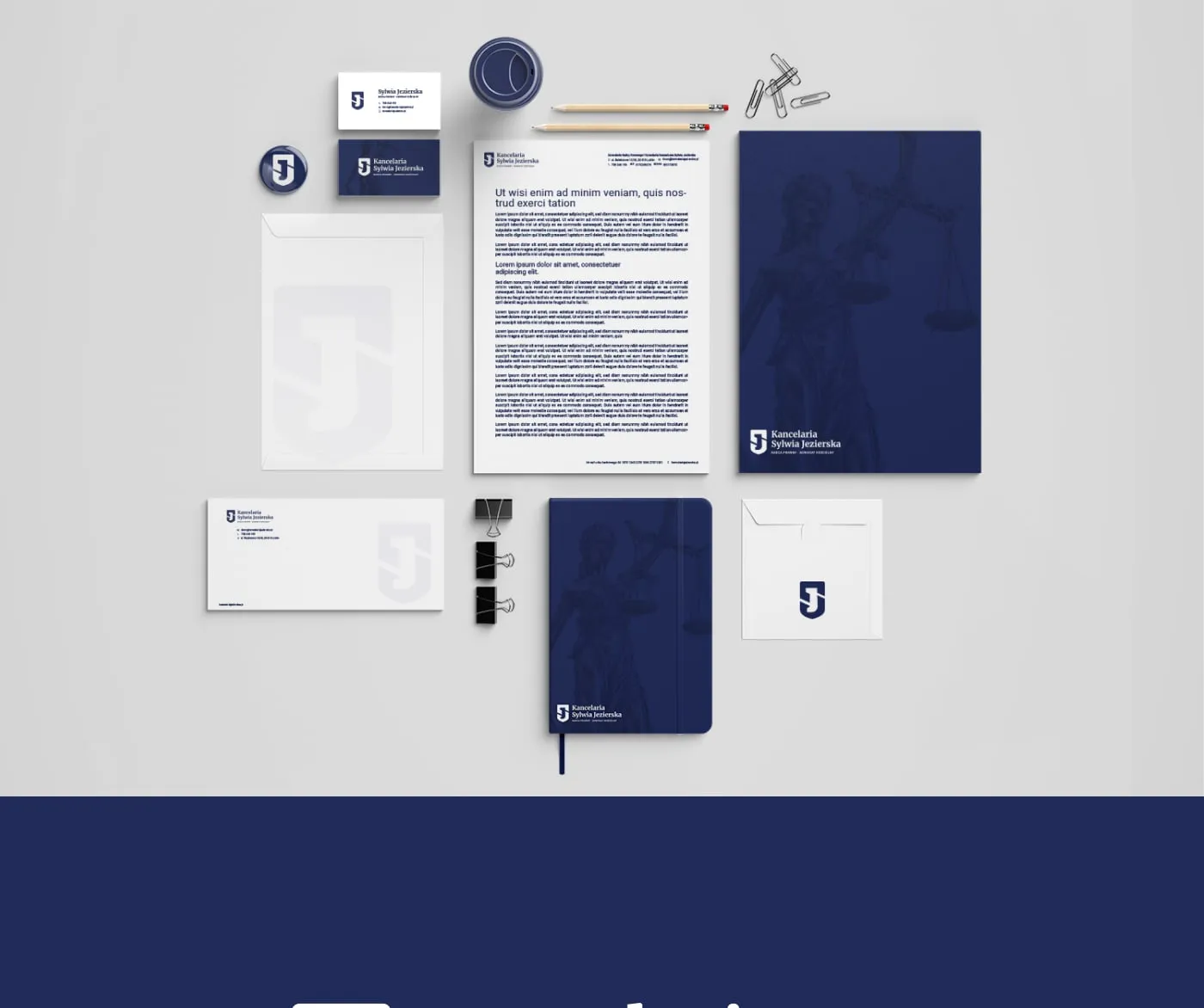 Kancelaria Sylwia Jezierska - flat-lay papeterii firmowej (papier firmowy, wizytówki, koperta, notes, teczka z sylwetką Temidy) na jasnym tle.