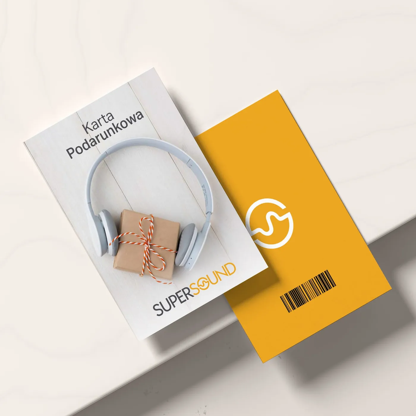 Supersound - dwustronna karta podarunkowa: awers ze słuchawkami na zapakowanym prezencie i napisem „Karta Podarunkowa", rewers w pomarańczowym kolorze z logo i kodem kreskowym.